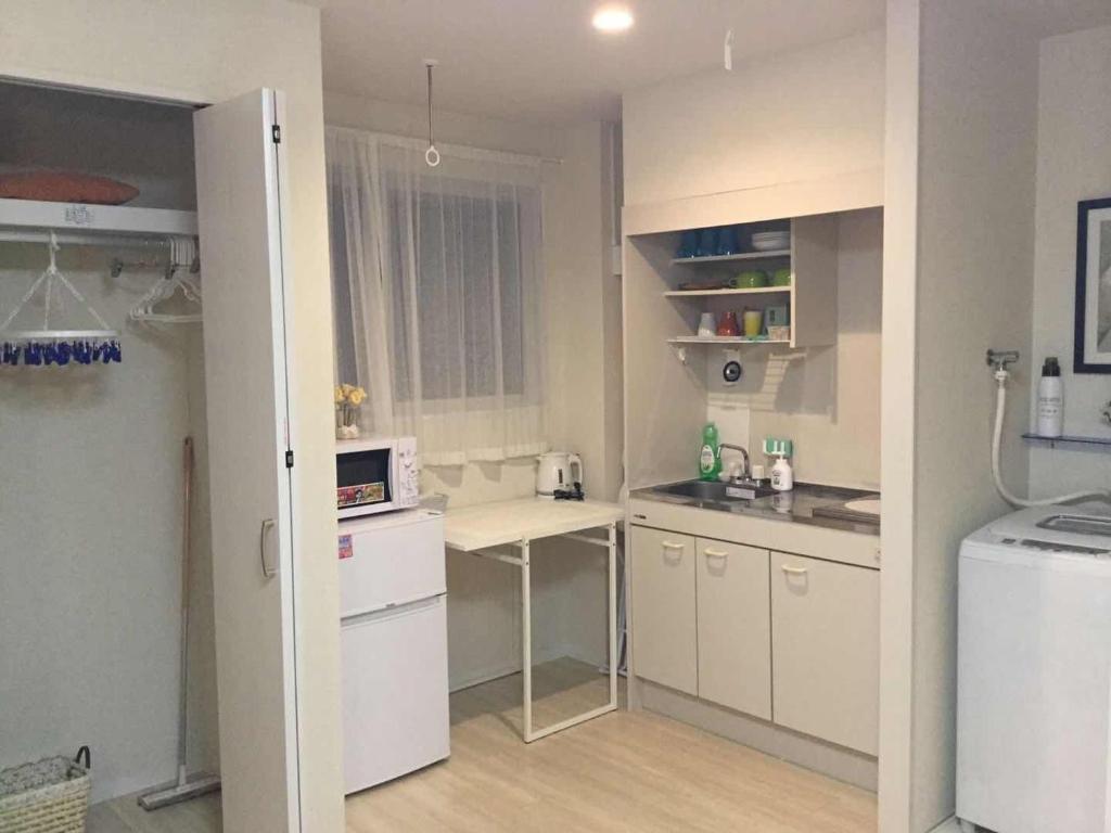 a small kitchen with white cabinets and a white refrigerator at 駅近-JR小岩駅まで徒歩3分-Leo小岩 101 in Tokyo