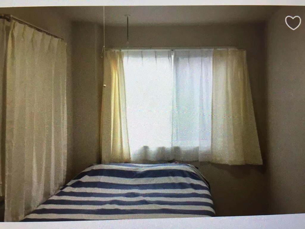 a bedroom with a window and a bed with a striped pillow at 駅近-JR小岩駅まで徒歩3分 Leo小岩203 in Tokyo