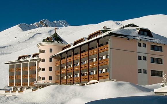 un edificio nella neve di fronte a una montagna di Sporthotel Kühtai a Kühtai