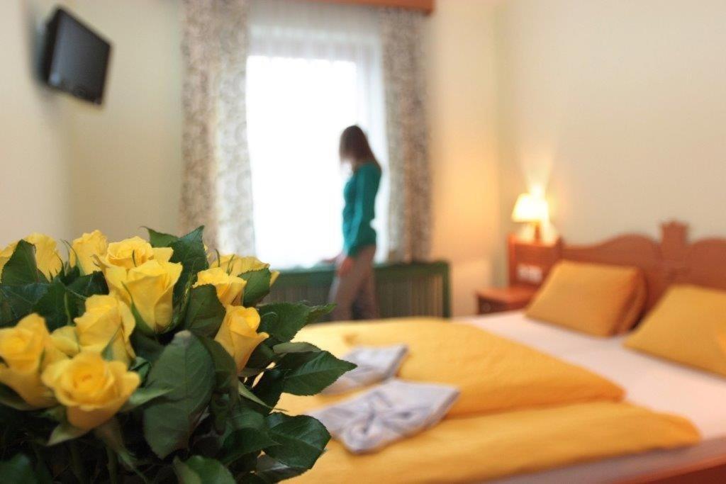 a woman standing in a bedroom with a bed with yellow roses at Gasthof Gnasmüller in Totzenbach