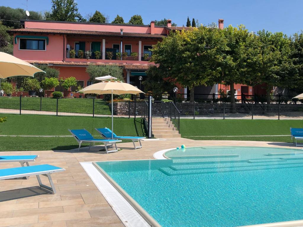 - une piscine avec des chaises et des parasols en face d'un bâtiment dans l'établissement Al Colle, à Cavaion Veronese