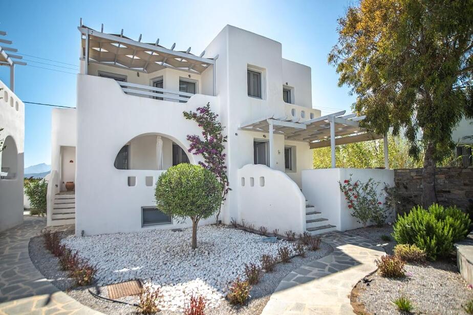 Una casa blanca con un árbol delante. en Casa Famiglia en Agios Prokopios
