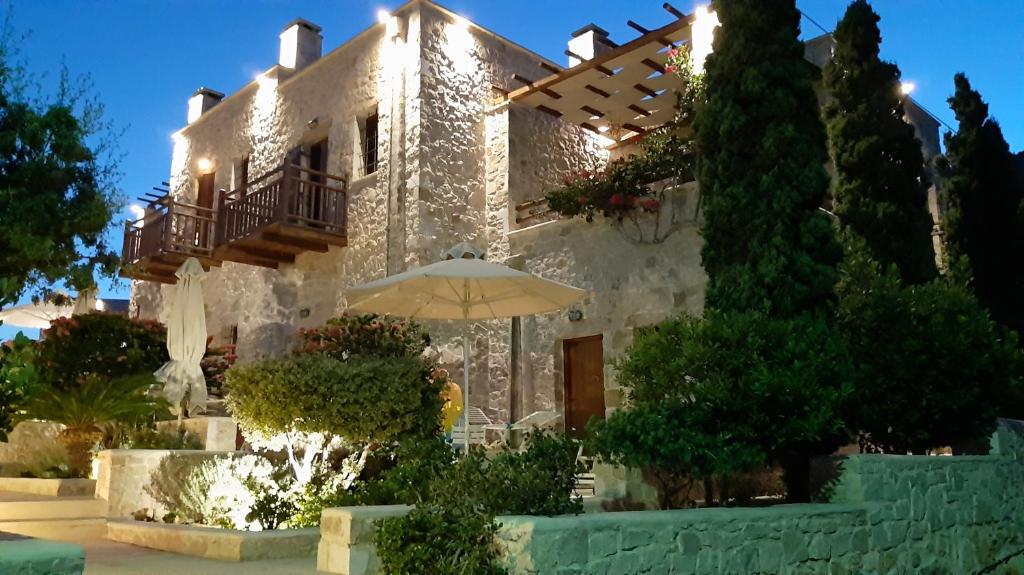 une maison avec un parasol devant elle dans l'établissement Lithos Traditional Guest Houses, à Xerokampos