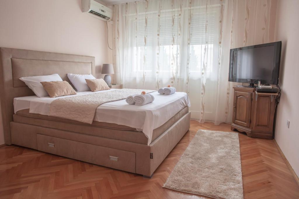 a bedroom with a large bed and a flat screen tv at Apartman Preko Morace 2018 in Podgorica