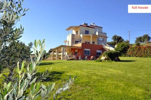 a house sitting on top of a lush green field at Electra Private Villas in Kassandra