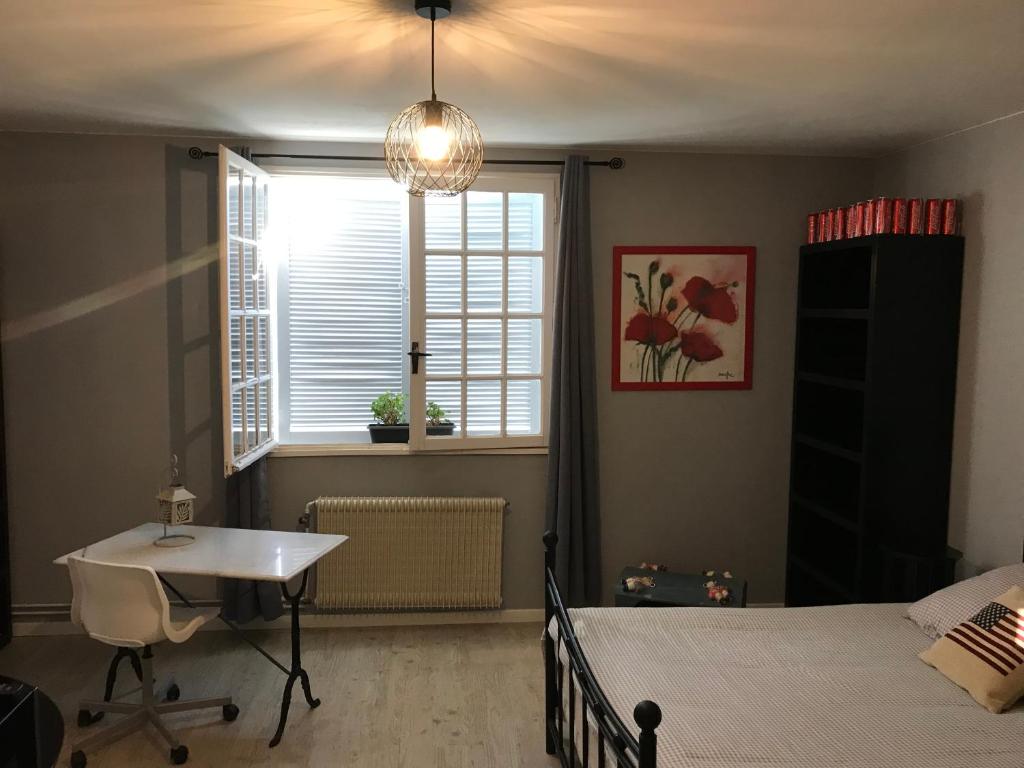 um quarto com uma cama, uma secretária e uma janela em La pause nuitonne em Nuits-Saint-Georges