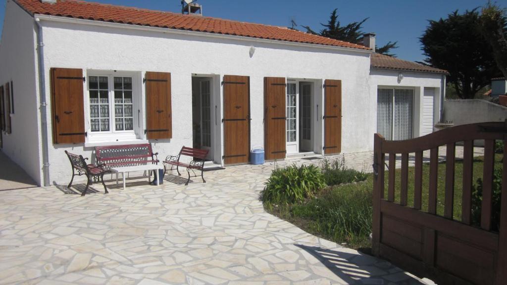 un patio con 2 sillas y un banco frente a una casa en Location La Brée les Bains 15 personnes, en La Brée-les-Bains