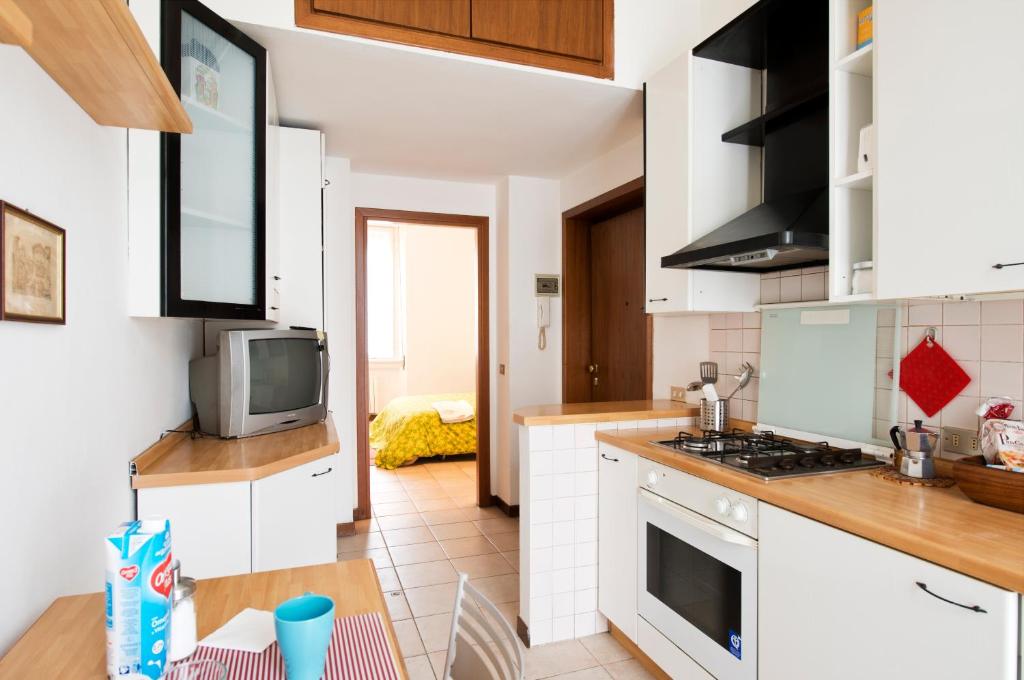 a kitchen with white cabinets and a tv on a counter at Milanofiere Flat in Milan