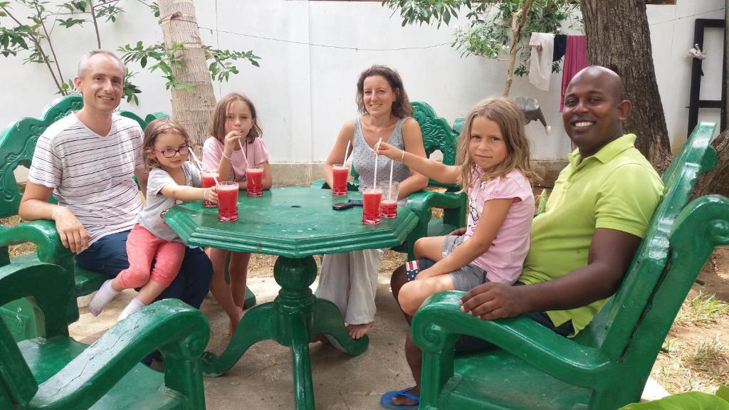 Una familia sentada en una mesa con sillas verdes. en Freedom Lodge Yala, en Tissamaharama