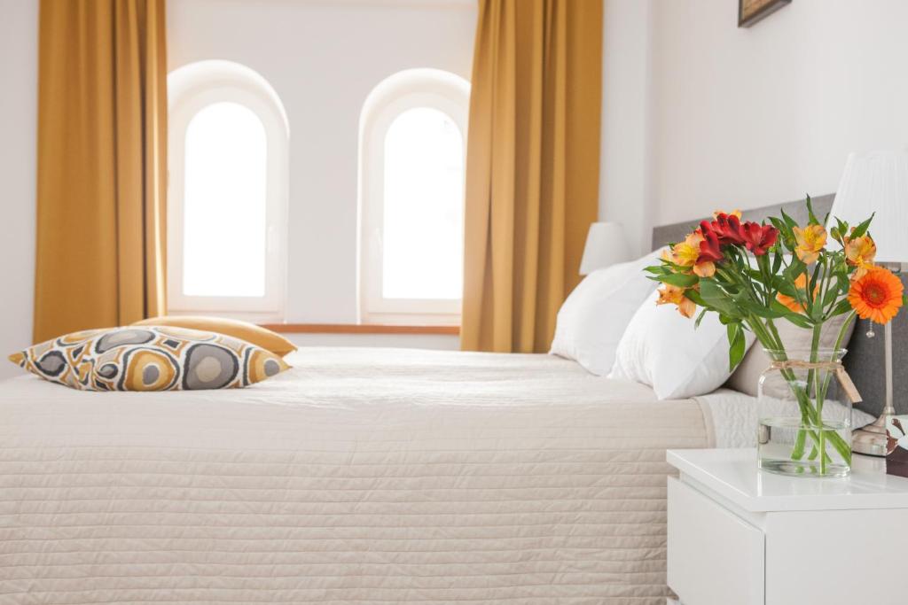 um quarto com uma cama com um vaso de flores sobre uma mesa em Apple Inn em Varósvia