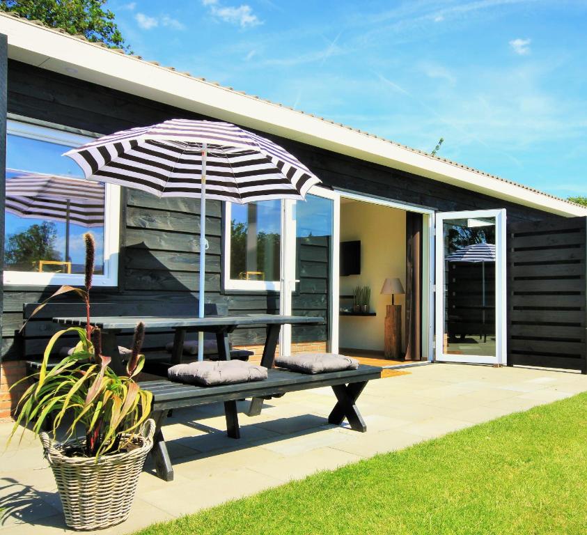 a picnic table with an umbrella in front of a house at B&B Beach&Bos in Oostvoorne