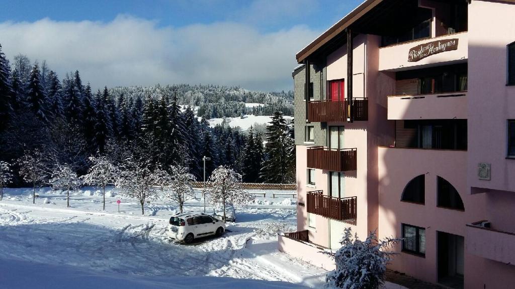 un coche aparcado en la nieve al lado de un edificio en Appartement dernier étage au pied des pistes HIRMENTAZ, en Bellevaux