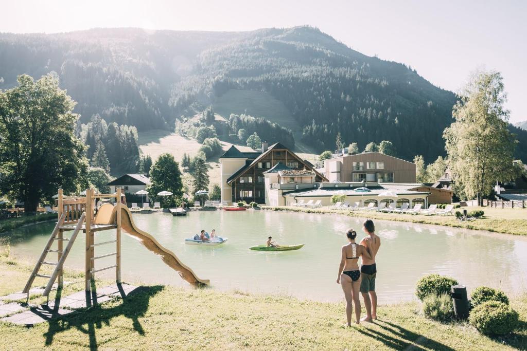 Kinderhotel Stegerhof في دونيغسباشوالد: شخصين بملابس السباحة تقف بجانب البحيرة