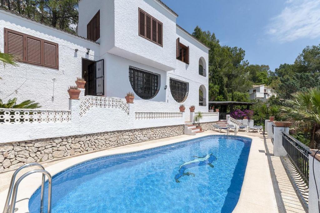a villa with a swimming pool in front of a house at Casabra in Palma de Gandía