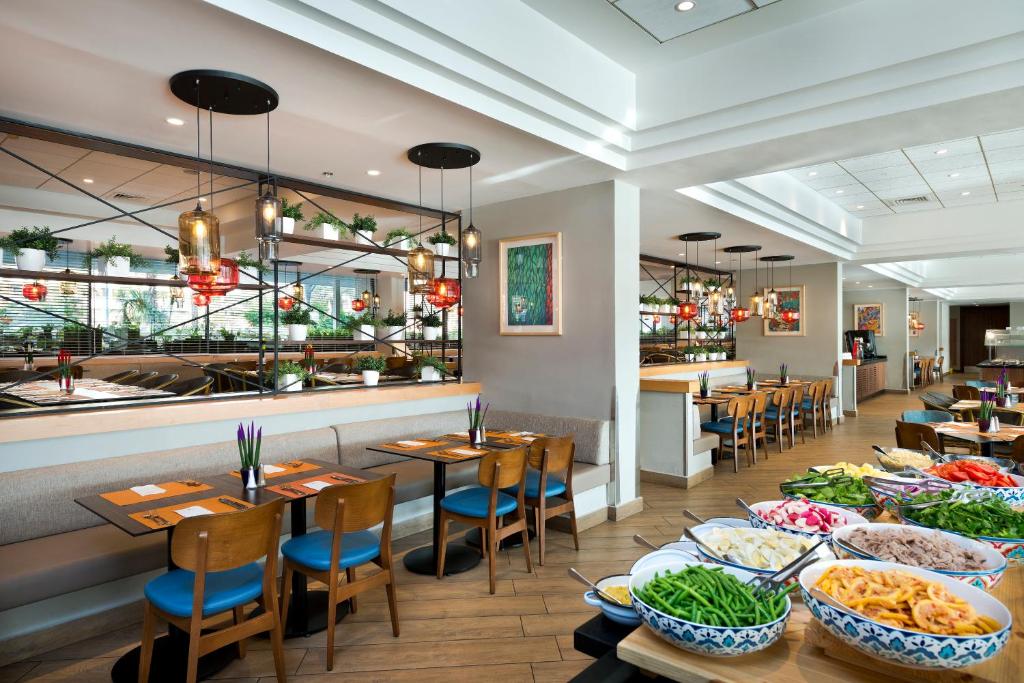 ein Restaurant mit Tischen und Stühlen, auf denen Essen steht in der Unterkunft Lagoona by Isrotel Collection in Eilat