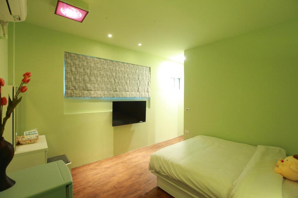 a green bedroom with a bed and a window at Fasiter B&amp;B train station in Hualien City