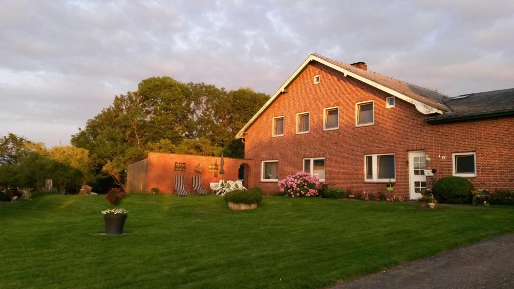 a large red brick house with a green yard at Ferienhof Friedenshof Hafer in Vollerwiek