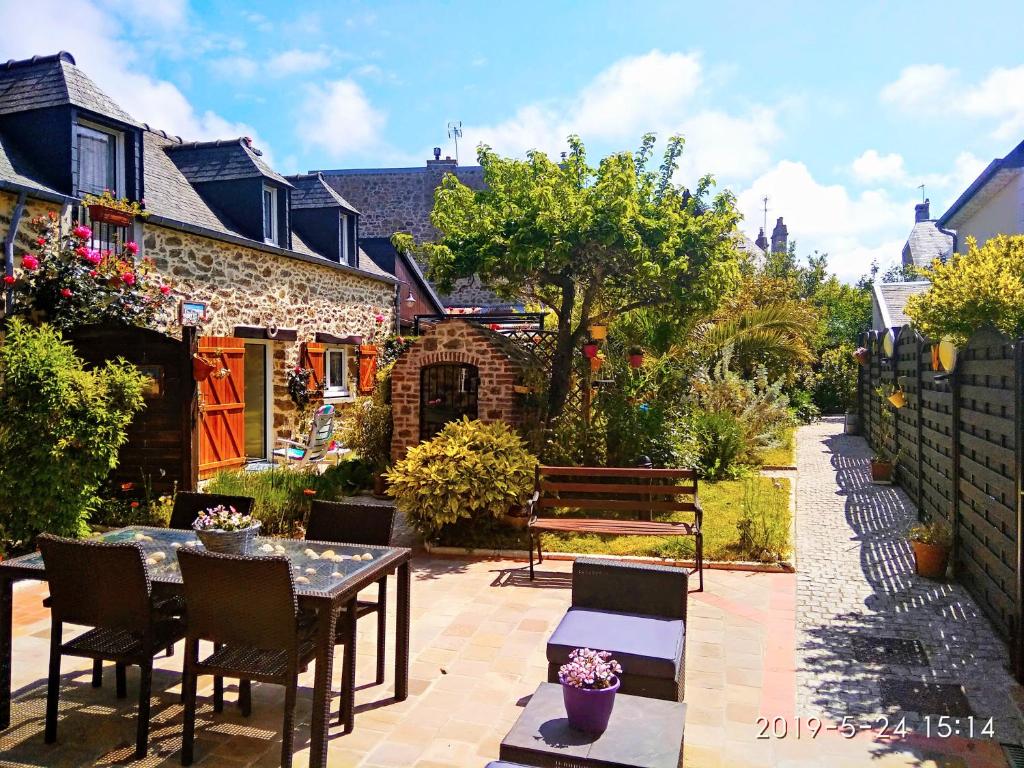 un patio con tavolo, sedie e panca di Gites De La Cote D'emeraude a Dinard