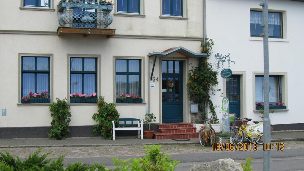 a white house with a blue door and windows at Hotel Spitzenhoernbucht in Wolgast