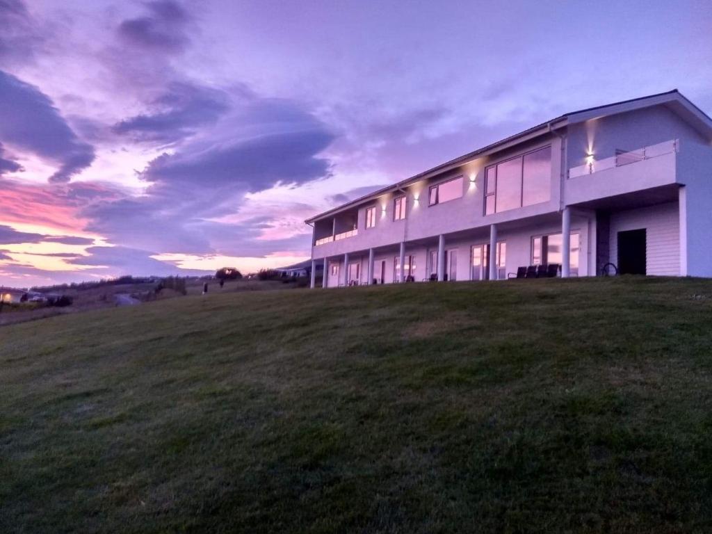 a large building in a field with a sunset at Hafdals Hotel in Akureyri