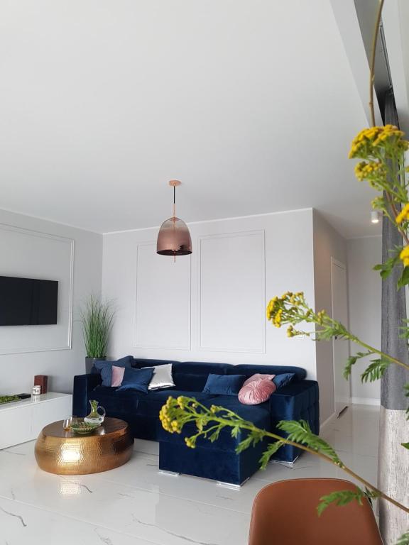 Apartament MARCELIN GOLD Wes Quality Suite في بوزنان: غرفة معيشة مع أريكة زرقاء وطاولة