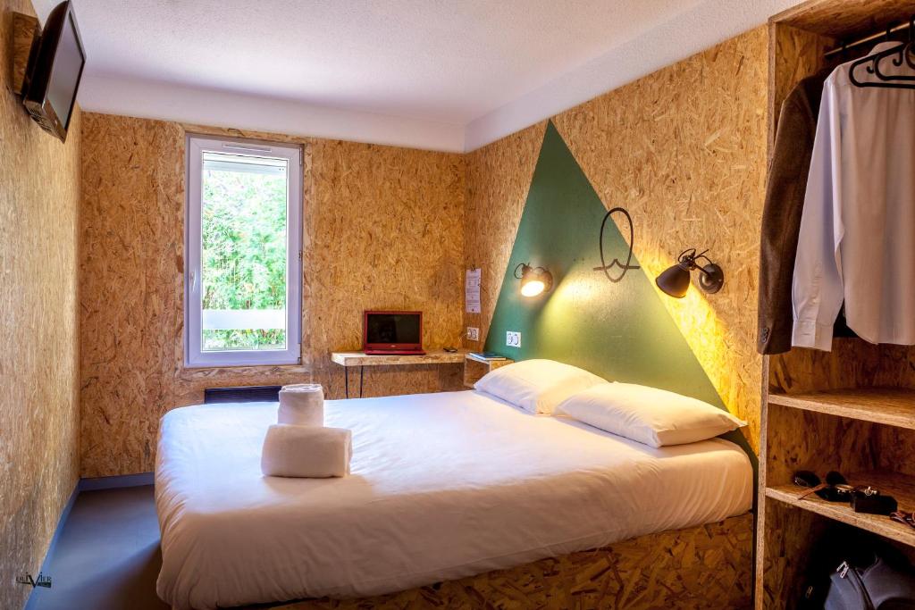 una camera da letto con un grande letto bianco e una finestra di Hôtel Moustache Lille - Seclin a Seclin