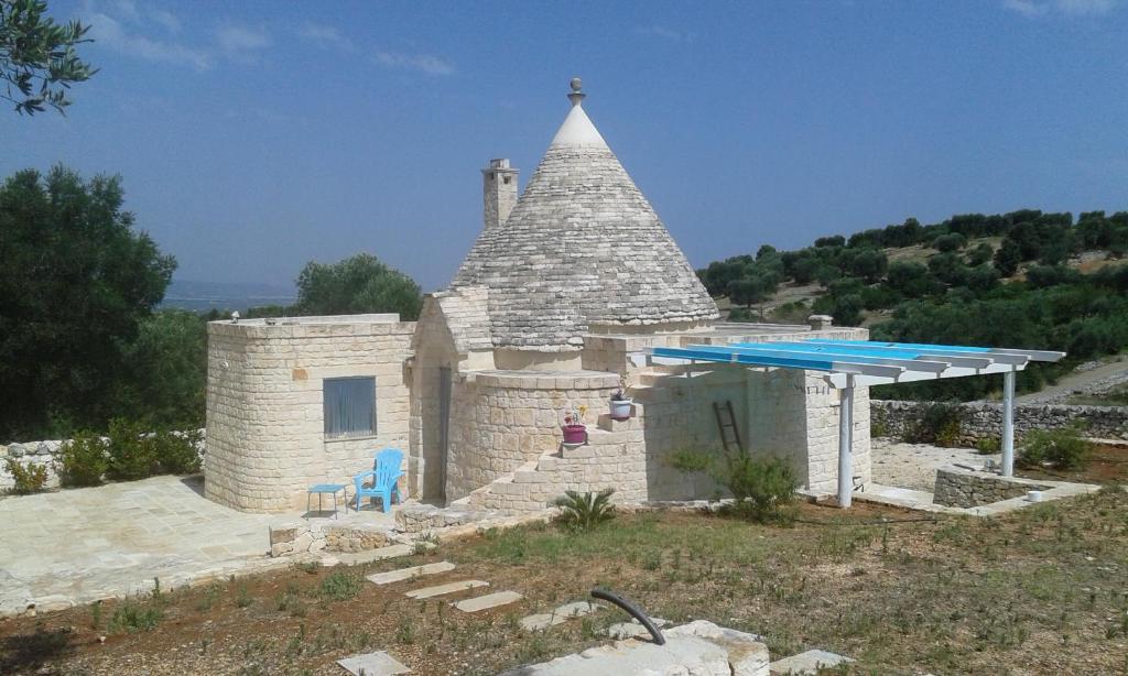 un piccolo edificio in pietra con tetto a piramide e piscina di Trullo Alto Salento a Cisternino