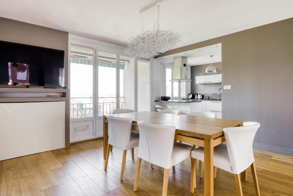 une cuisine et une salle à manger avec une table en bois et des chaises blanches dans l'établissement Superbe Appart 3ch Terrasse Vue sur Lyon et garage, à Lyon