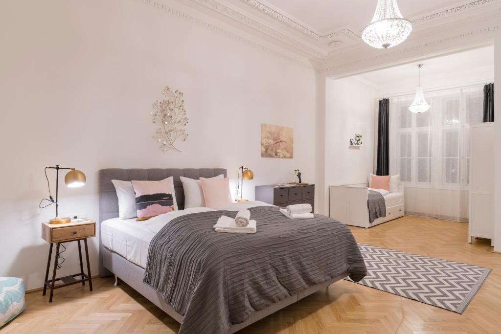 a white bedroom with a large bed and a chair at Palais Schottentor in Vienna