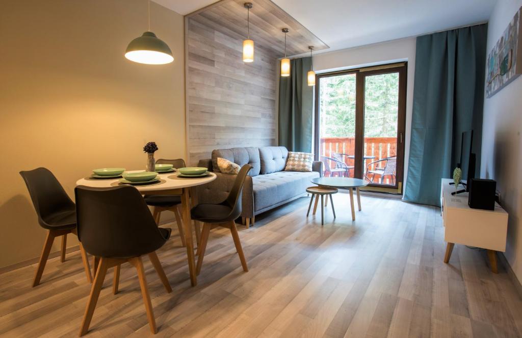 een woonkamer met een tafel en stoelen en een bank bij Chopok Juh - Ambiente Apartment in Tale