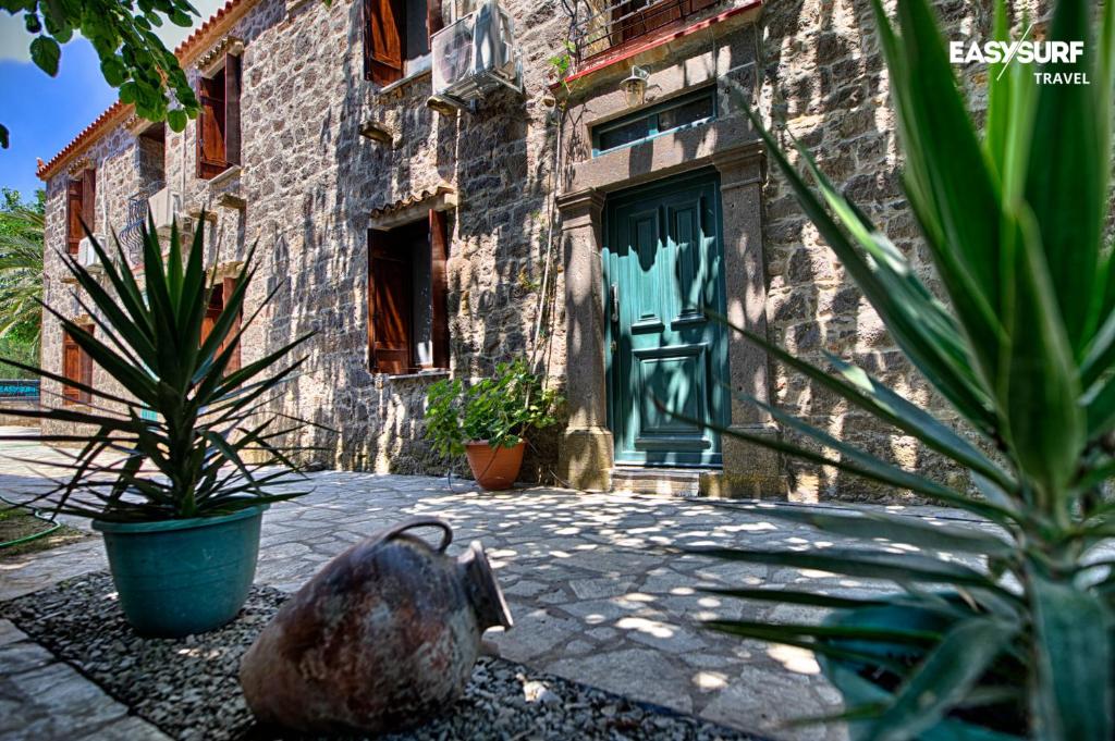Stone House Limnos في Repanídhion: مبنى فيه باب أخضر وبعض النباتات