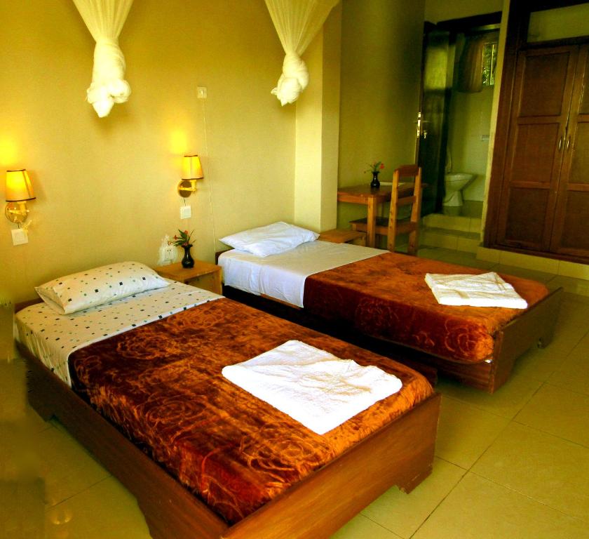 a hotel room with two beds and a bathroom at Rebero Kivu Resort in Kibuye