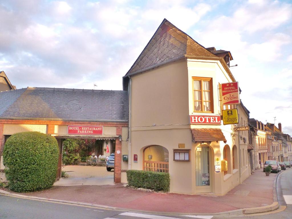 a building on the corner of a street with a hotel at Hotel Restaurant Le Cygne in Conches-en-Ouche