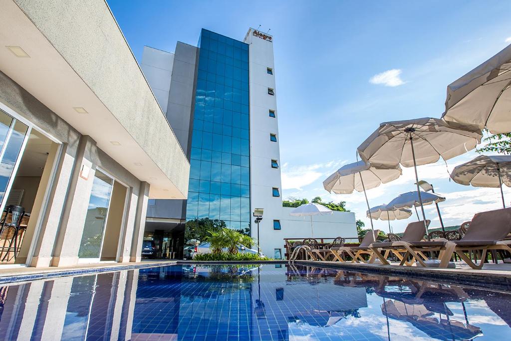 a pool with chairs and umbrellas next to a building at Alegro Hotel in Jarinu