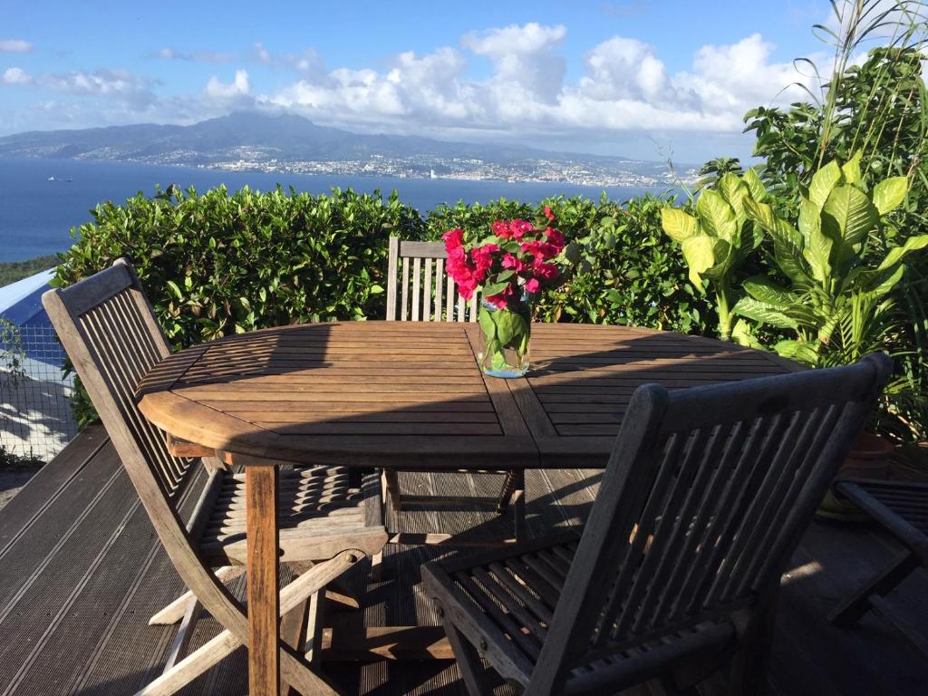 a wooden table with a vase of flowers on a deck at BAY VIEW MARTINIQUE in Les Anses-dʼArlets