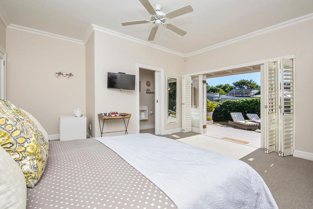 a bedroom with a bed with a ceiling fan at Bollard Bay House in Knysna