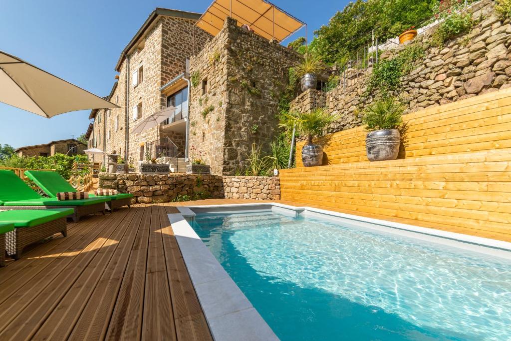 a swimming pool with a wooden deck and a house at La Calade Chambres d'Hôtes & Espace Bien-Etre in Chirols