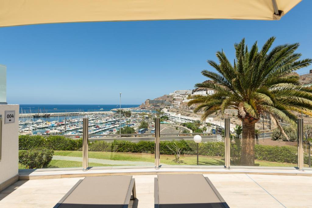 a balcony with a palm tree and a view of a harbor at Holiday Club Puerto Calma in Puerto Rico de Gran Canaria