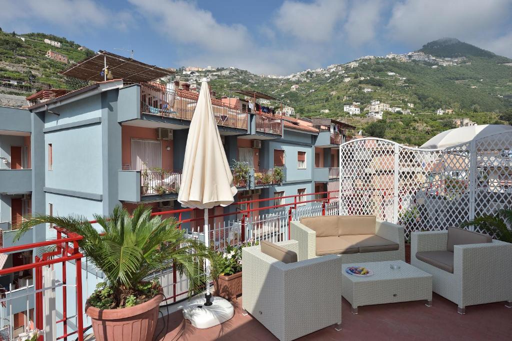 balkon z parasolem i krzesłami oraz budynek w obiekcie Costa d'Amalfi Apartments w mieście Minori