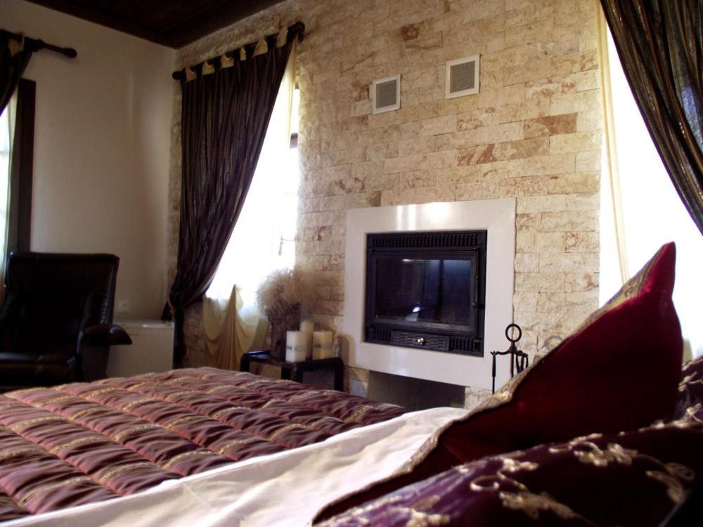 a bedroom with a large bed and a stone wall at Panorama Prespes in Agios Germanos