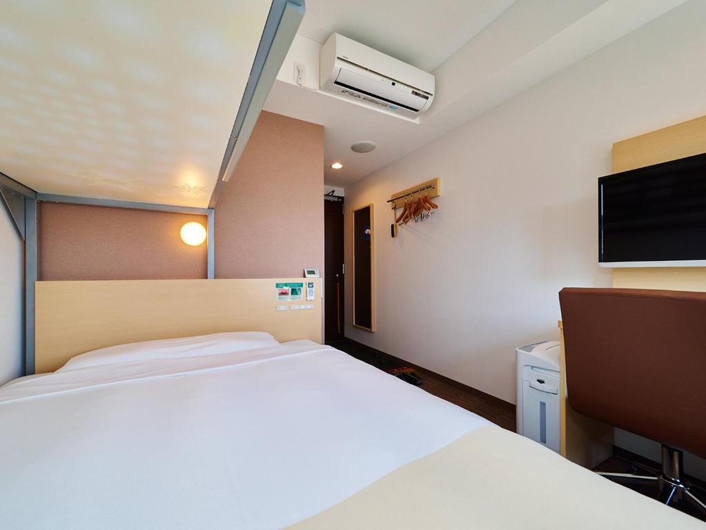 a hotel room with a bed and a tv at Super Hotel Akihabara Suehirocho in Tokyo