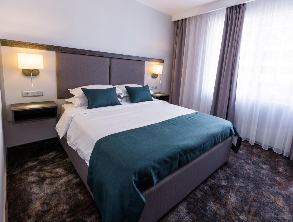 a hotel room with a large bed with blue pillows at Best Western PLUS Premium Inn in Sunny Beach