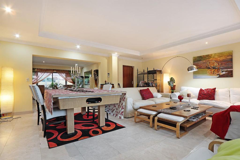 a living room with a table and a couch at Natalie Guesthouse in Bloubergstrand
