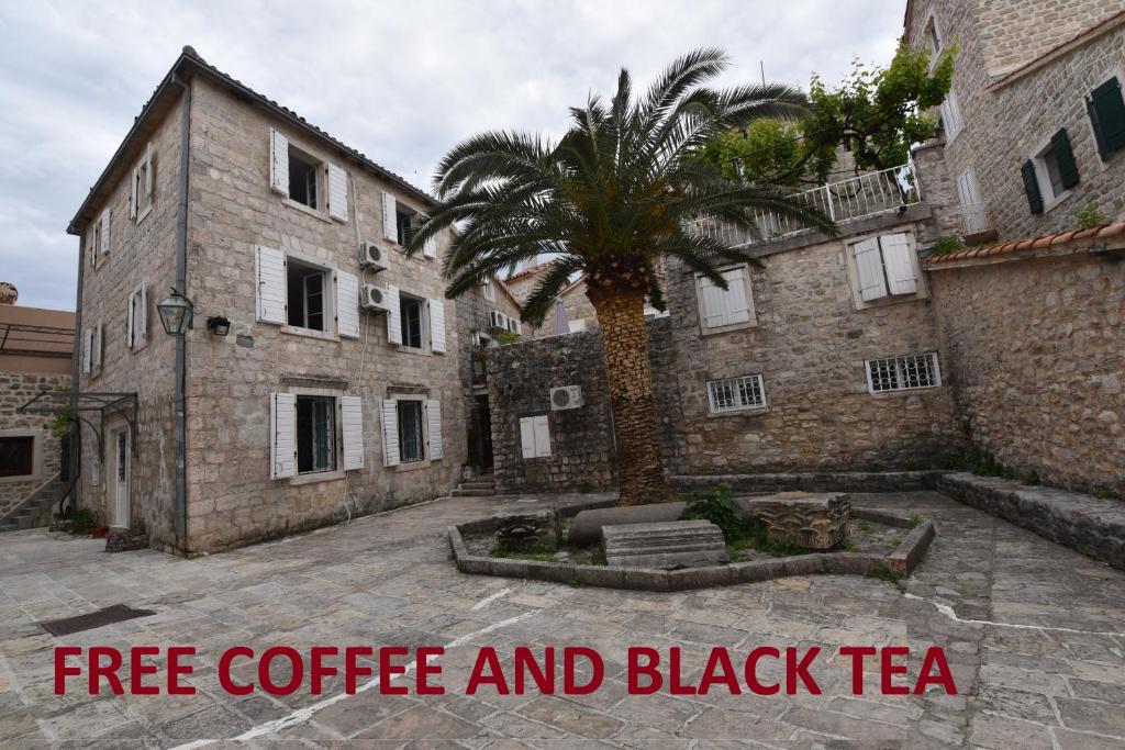 a building with a palm tree and a black tea sign at Hostel Michel in Budva