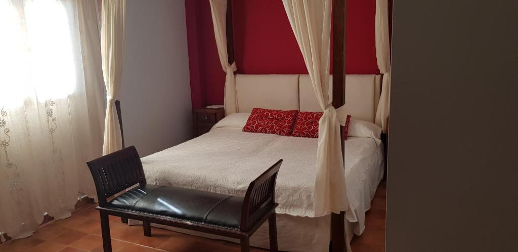 a bedroom with a bed with a chair and a window at Apartamentossierradegata La Noguera villamiel in Villamiel
