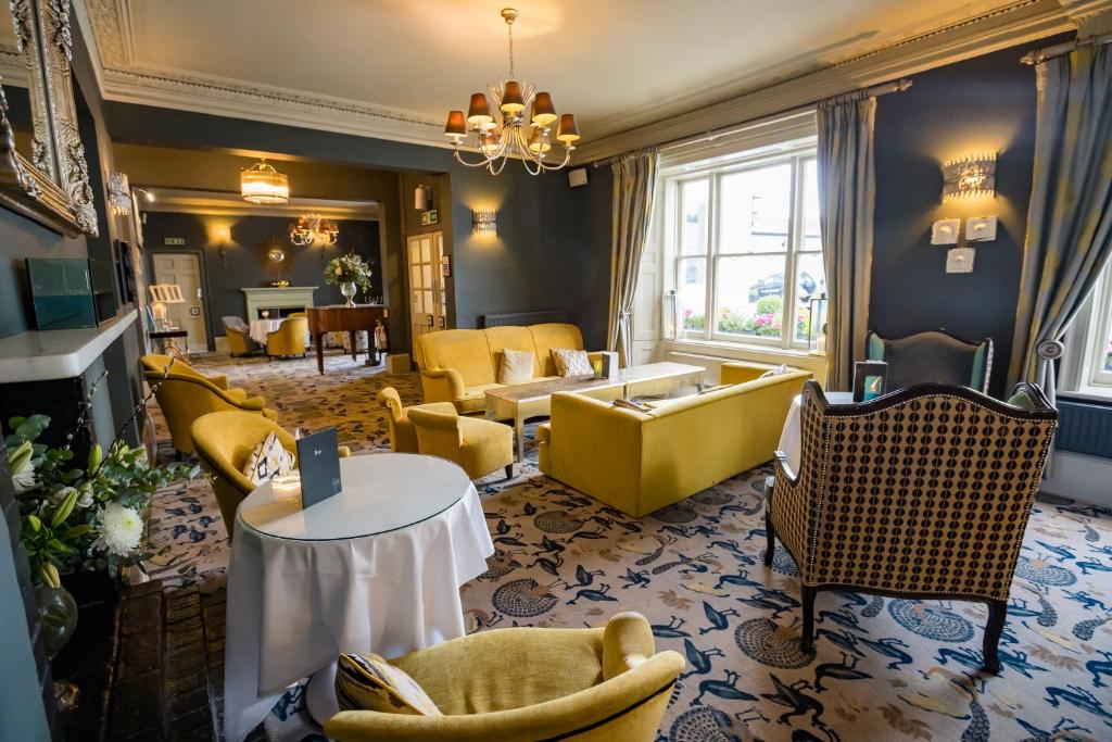 una sala de estar con muebles amarillos y sillas amarillas. en Woughton House Hotel, en Milton Keynes