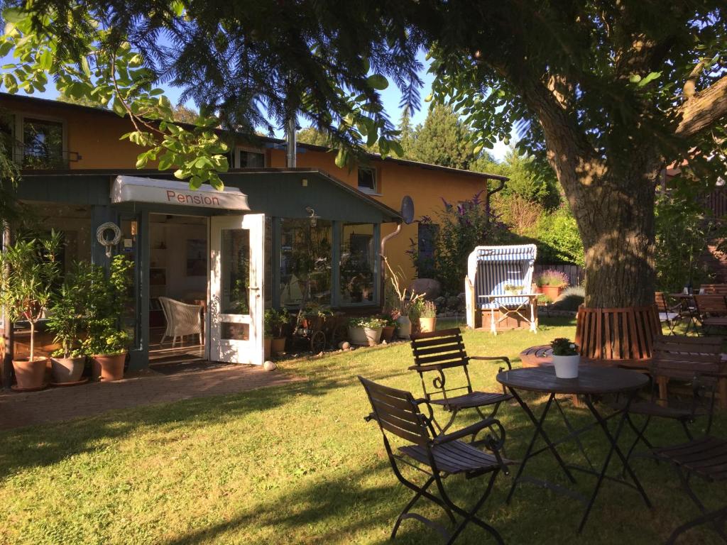 une table et des chaises sous un arbre dans une cour dans l'établissement Pension am Hochufer, à Lohme