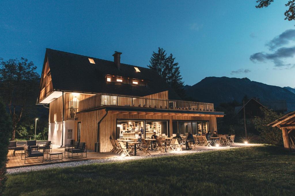 ein großes Haus mit Tischen und Stühlen im Hof in der Unterkunft Hotel Majerca in Bohinj