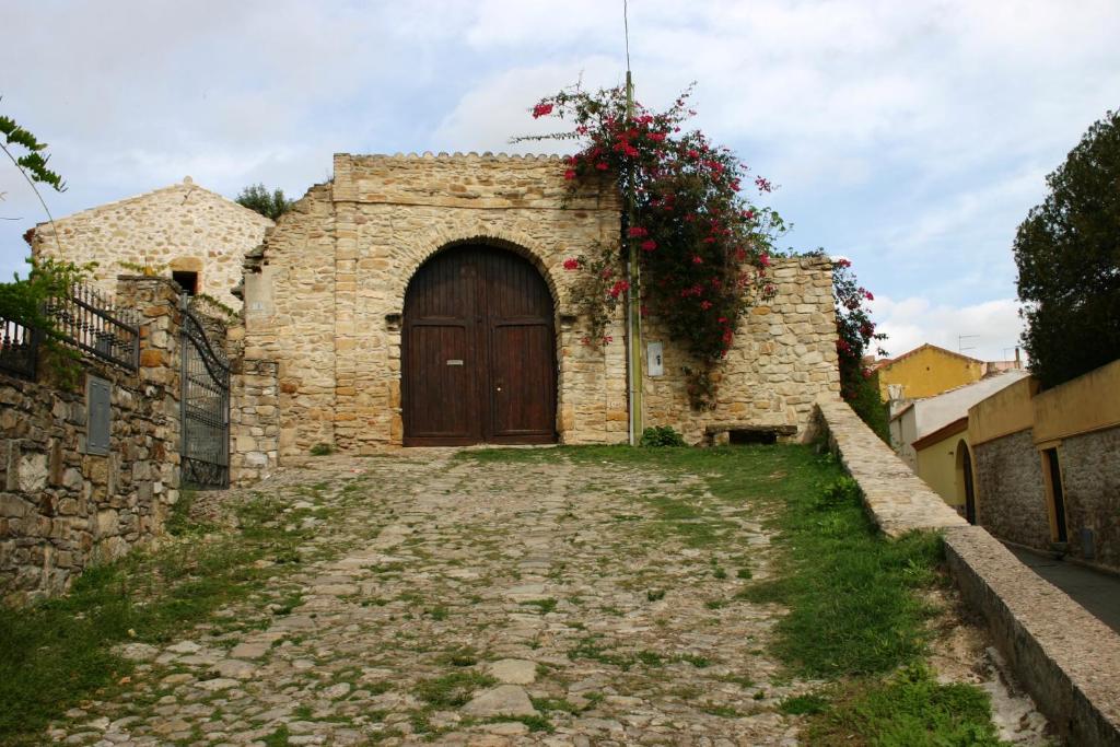 un vecchio edificio in pietra con una porta con dei fiori sopra di Sa Domu de sa Contissa a Sèlegas