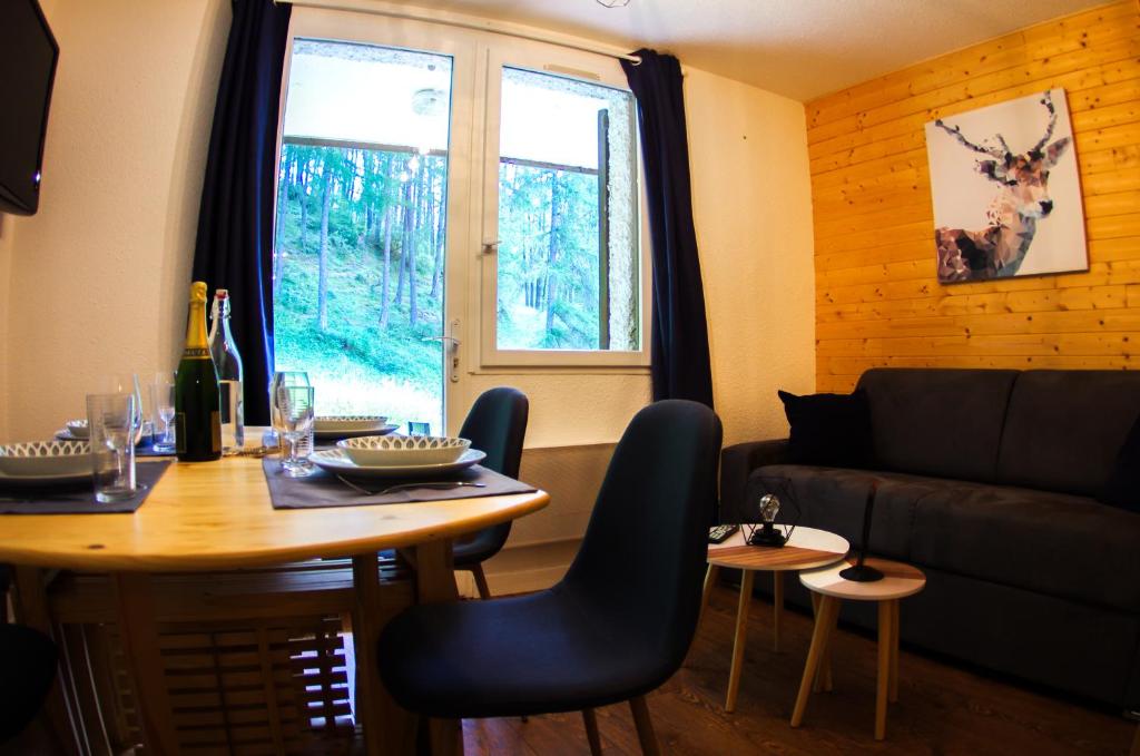 a living room with a table and a couch at L'Orée des Bois - Studio avec terrasse au calme in Les Orres